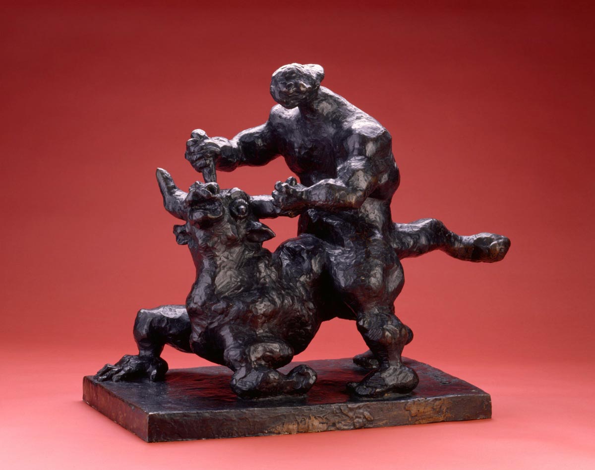 Black sculpture of a man grabbing a minotaur by the horns