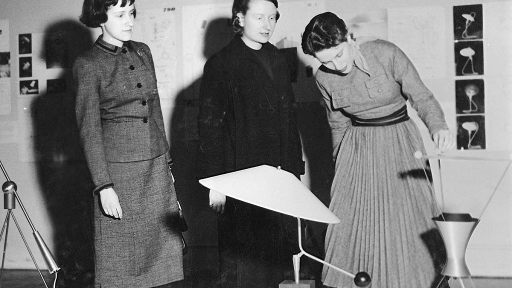 Three women looking at a lamp in an exhibition