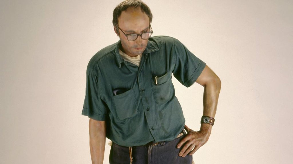 Lifelike Janitor sculpture leaning against a wall